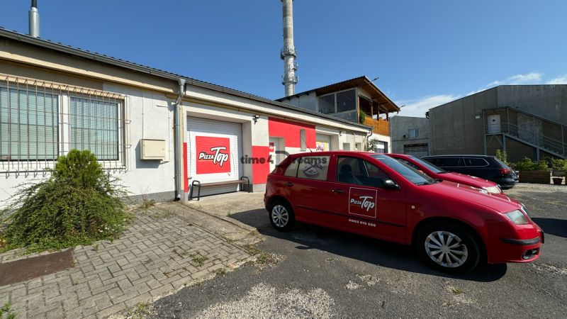 ODSTÚPENIE gastro prevádzky PIZZA Top v Nitre - Vonku je parkovisko s logo Pizza Top, okolo sú priemyselné gastro priestory.