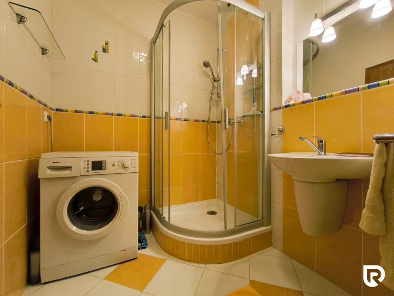| priestranný | 2i byt s balkónom | parkovaním | Koprivnická - Kúpeľňa v 2-izbovom byte s práčkou, sprchovacím kútom a žltými obkladačkami.