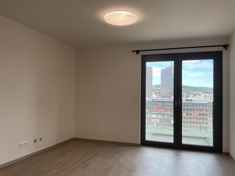 I Predaj Výnimočný  1-izb apartmán v projekte Metropolis - Obývacia izba v 1-izbovom byte s podlahou s dreveným dekorom a veľkým oknom na balkón.