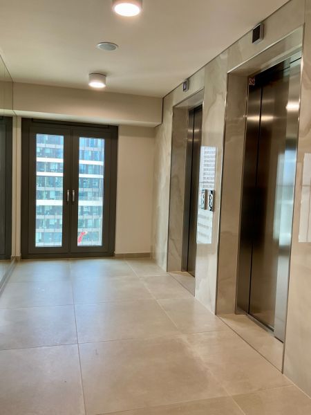 I Predaj Výnimočný  1-izb apartmán v projekte Metropolis - Výťahová hala v budove Bratislava - Staré Mesto so sklenými dverami a svetlými obkladačkami.