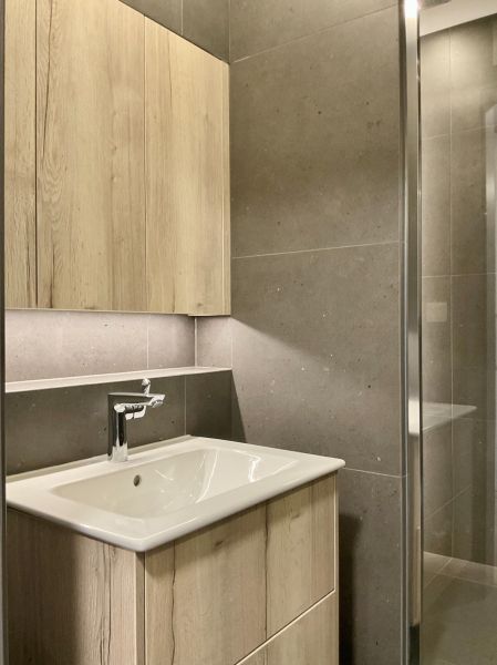 I Predaj Výnimočný  1-izb apartmán v projekte Metropolis - Kúpeľňa so svetlým dreveným nábytkom a tmavými obkladmi v 1-izbovom byte.