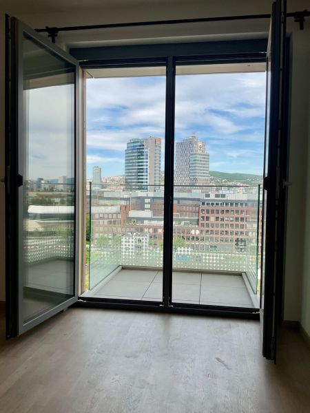 I Predaj Výnimočný  1-izb apartmán v projekte Metropolis - Výhľad na centrum Bratislavy z 1-izbového bytu s balkónom a podlahou s dreveným dekorom.