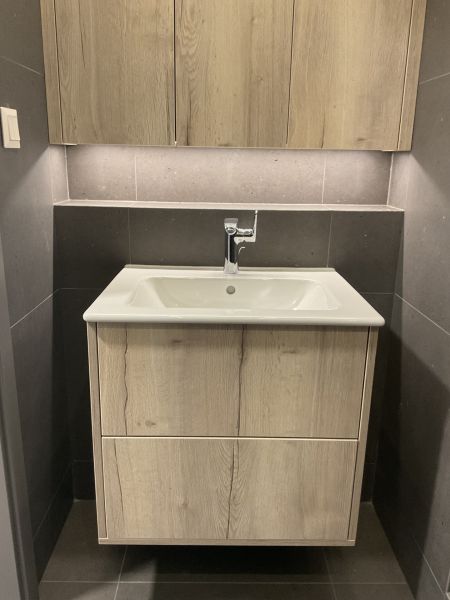 I Predaj Výnimočný  1-izb apartmán v projekte Metropolis - Kompaktná kúpeľňa so skrinkou a umývadlom v 1-izbovom byte, svetlé drevo a tmavé obklady.