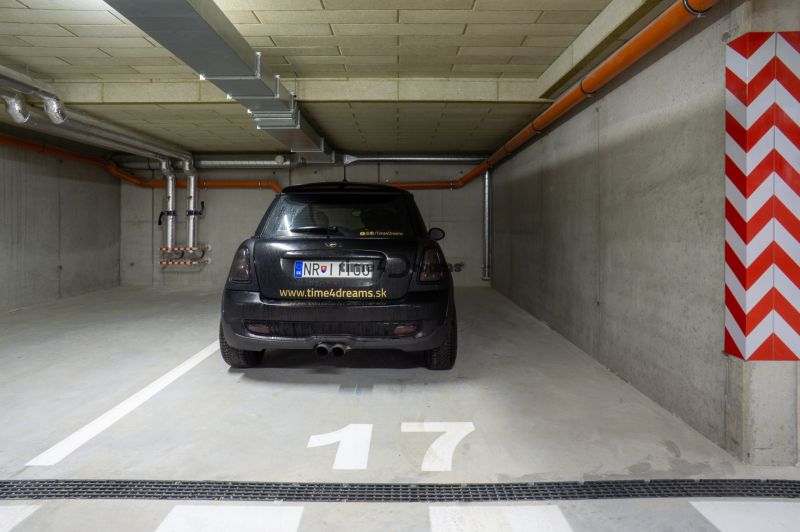 NA PRENÁJOM  2 izbový byt s GARÁŽOU Nitra - Parkovacie miesto v garáži s nápisom na aute, číslom 17 a potrubím na strope.