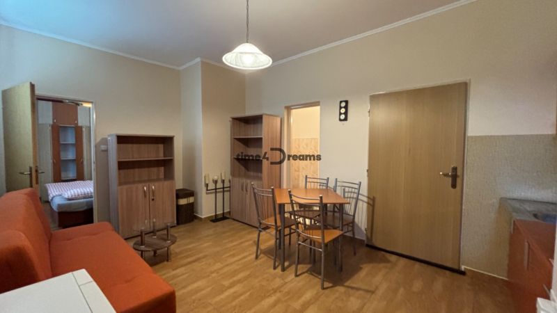 NA PREDAJ Ubytovňa v obci Bílkové Humence - Obývacia izba s oranžovým gaučom, jedálenským stolom a skriňami, pripomínajúca hotely a penzióny.