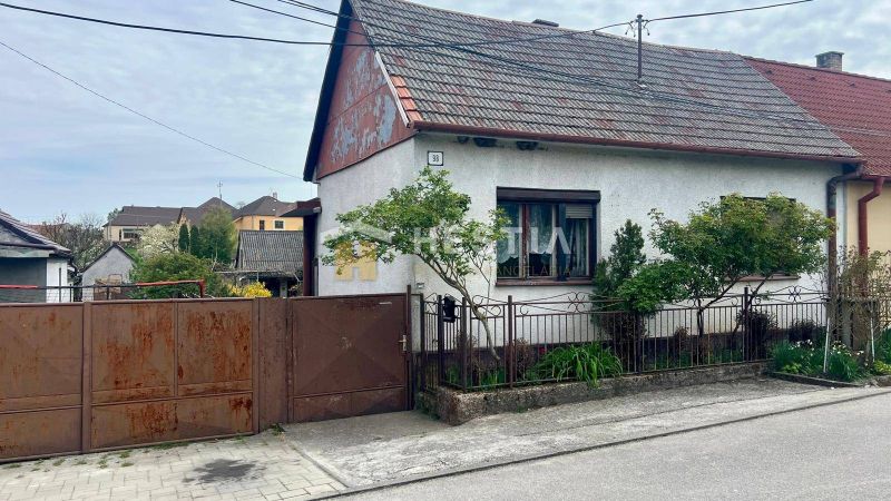NOVINKA NA TRHU | Rodinný dom v obci Cerová – ideálne miesto pre pokoj - Rodinný dom v Cerovej s bránou a malou záhradou, obkolesený zeleňou.
