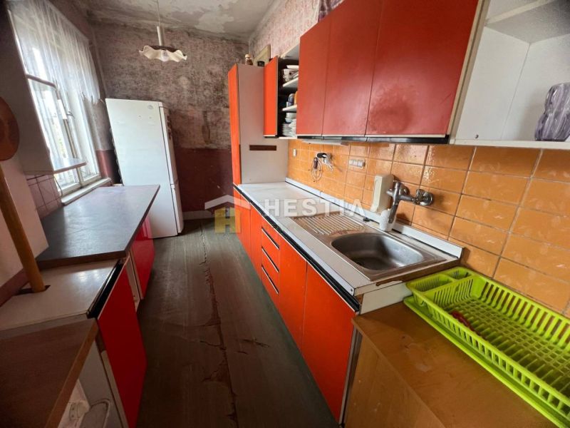 NOVINKA NA TRHU | Rodinný dom v obci Cerová – ideálne miesto pre pokoj - Kuchyňa v rodinnom dome s oranžovými skrinkami a podlahou s dreveným dekorom.