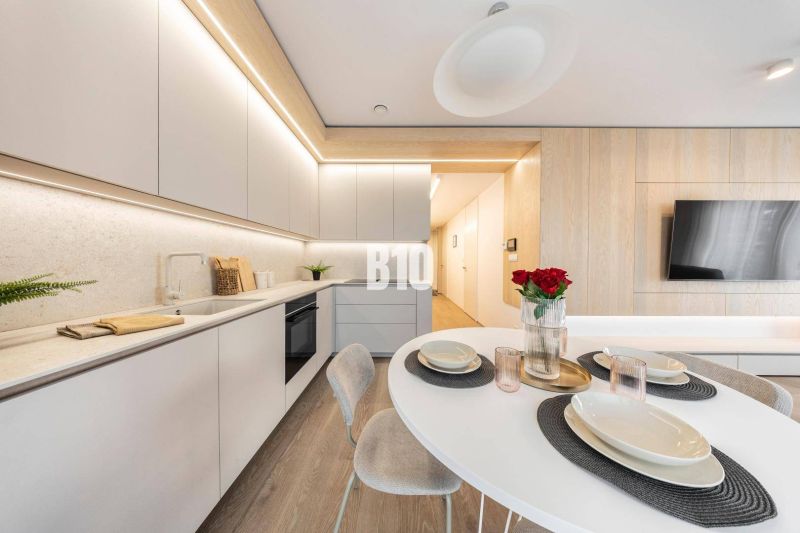 POD VINICAMI - 3IZBOVÉ BYTY V NADŠTANDARDNEJ BOUTIQUE REZIDENCII - Štýlová kuchyňa v 3-izbovom byte s podlahou s dreveným dekorom a moderným nábytkom.
