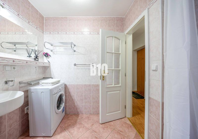 Praktický 2-izbový byt so samostatnou kuchyňou, Kvetná ulica – Nivy - Kúpeľňa s práčkou a ružovými kachličkami v 2-izbovom byte.