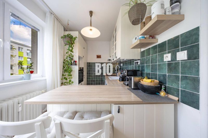 2-izbový byt po rekonštrukcii | Vietnamská ulica, Ružinov | Loggia | B - Kuchyňa v 2-izbovom byte s kuchynskou linkou, dreveným dekorom a zelenými obkladačkami.