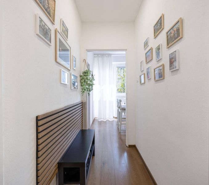 2-izbový byt po rekonštrukcii | Vietnamská ulica, Ružinov | Loggia | B - Chodba v 2-izbovom byte s dekorom podlahy a zavesenými obrázkami na stenách.