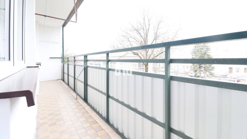 Na prenájom 3 izbový veľkometrážny byt Nováková ulica - Balkón 3-izbového bytu s výhľadom na stromy a dlažbou.