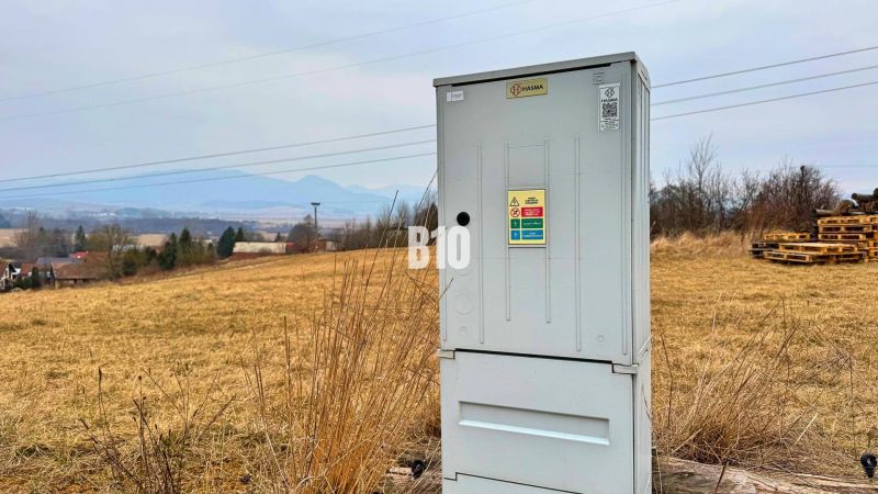 Veľký stavebný pozemok na predaj - Laskár - Elektrická skriňa na lúke, pozadie tvoria kopce a vidiecke bývanie.