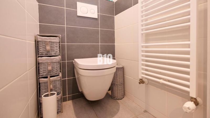Ideálne bývanie: Zariadený dom 85m² s nízkymi nákladmi - Toaleta v rodinnom dome s úložnými košmi a rebríkovým radiátorom.
