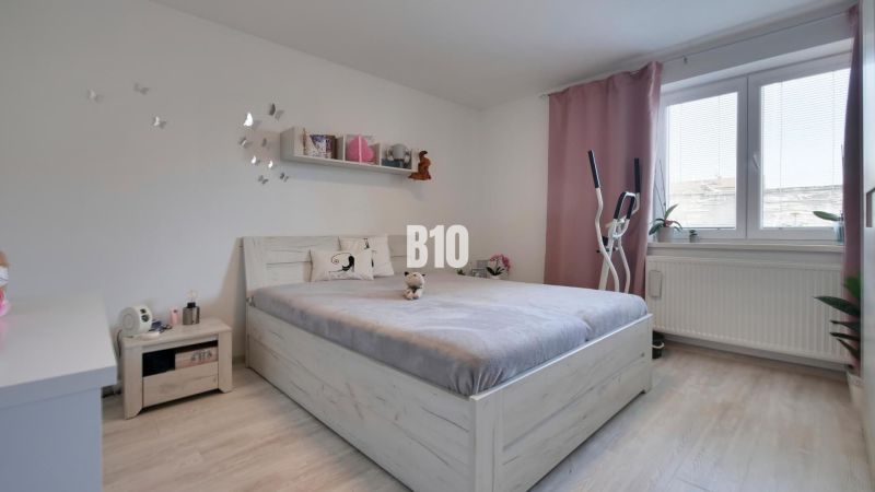 Ideálne bývanie: Zariadený dom 85m² s nízkymi nákladmi - Spálňa s posteľou, podlahou s dreveným dekorom a cvičebným zariadením v rodinnom dome.