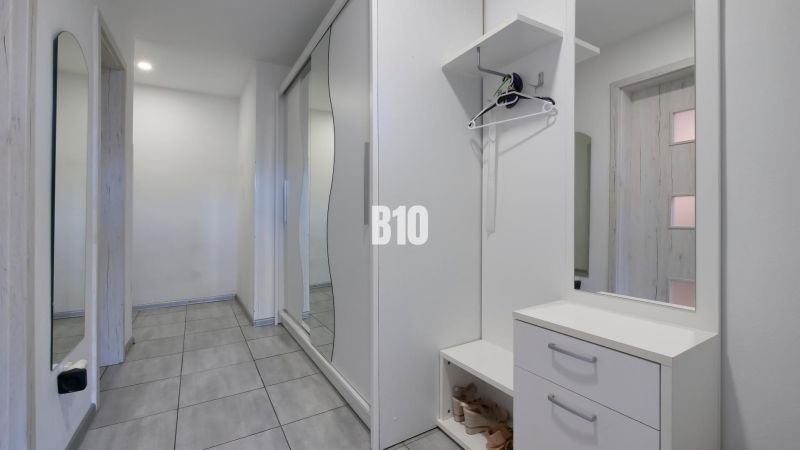 Ideálne bývanie: Zariadený dom 85m² s nízkymi nákladmi - Interiér rodinného domu s bielym nábytkom a veľkými zrkadlami v chodbe.
