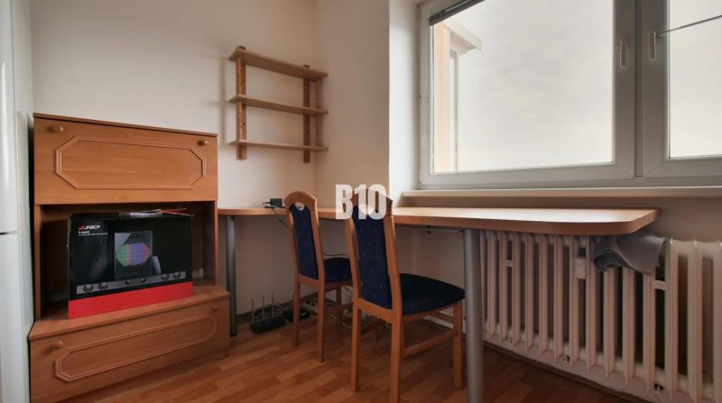 Predaj 1-izbového bytu po čiastočnej rekonštrukcii, Martin – Podháj - Pracovný kút s nábytkom a stoličkou, podlaha s dreveným dekorom, stena s policou.