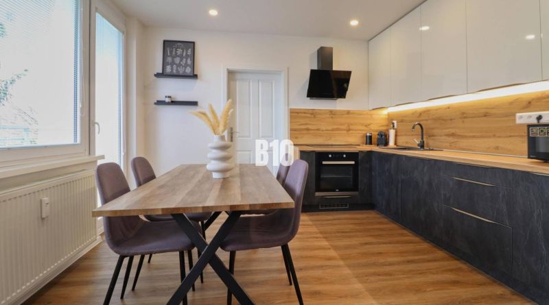 KRÁĽOVSKÝCH 82 m²: Kompletne zrekonštruovaný 3-izbový byt v centre Mar - Kuchyňa v 3-izbovom byte s dreveným dekorom, stolom a farebnými stoličkami.