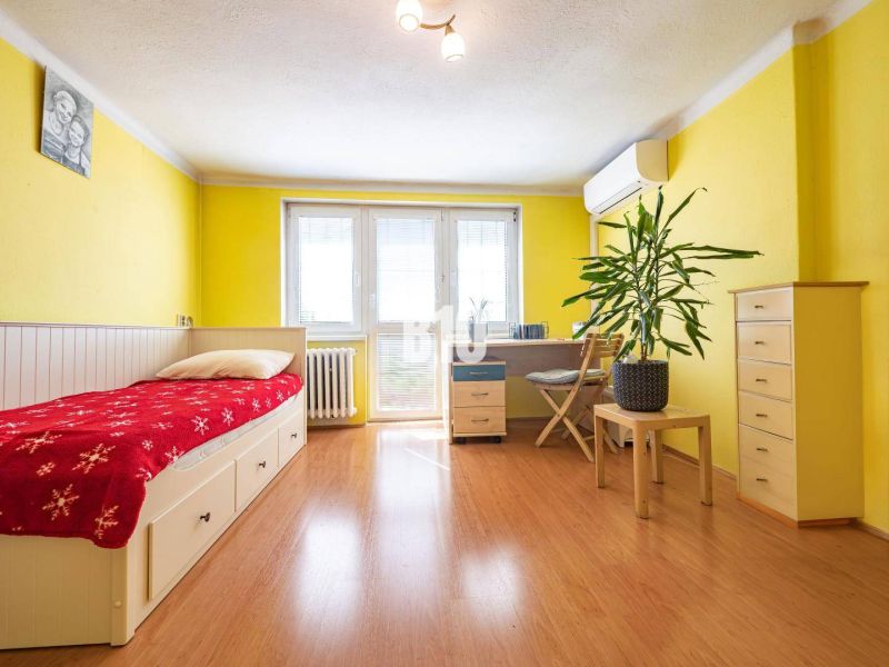 Prerobený 6i rodinný dom, krb a krásna záhrada, TOP lokalita, Zlaté Mo - Žltá izba s posteľou, pracovným stolom a podlahou s dreveným dekorom v rodinnom dome.