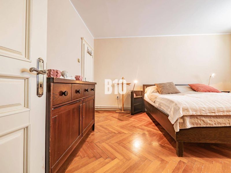 Prerobený 6i rodinný dom, krb a krásna záhrada, TOP lokalita, Zlaté Mo - Spálňa v rodinnom dome s podlahou s dreveným dekorom, posteľou a tmavým nábytkom.