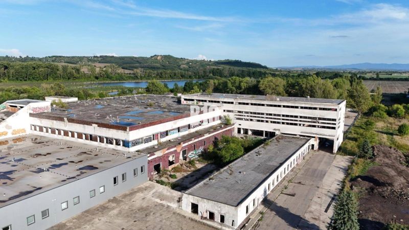 Veľkometrážne VÝROBNÉ HALY v priemyselnej zóne Géňa - Levice - Výrobné priestory v Leviciach s opustenými budovami obklopené prírodou a vodnou plochou.