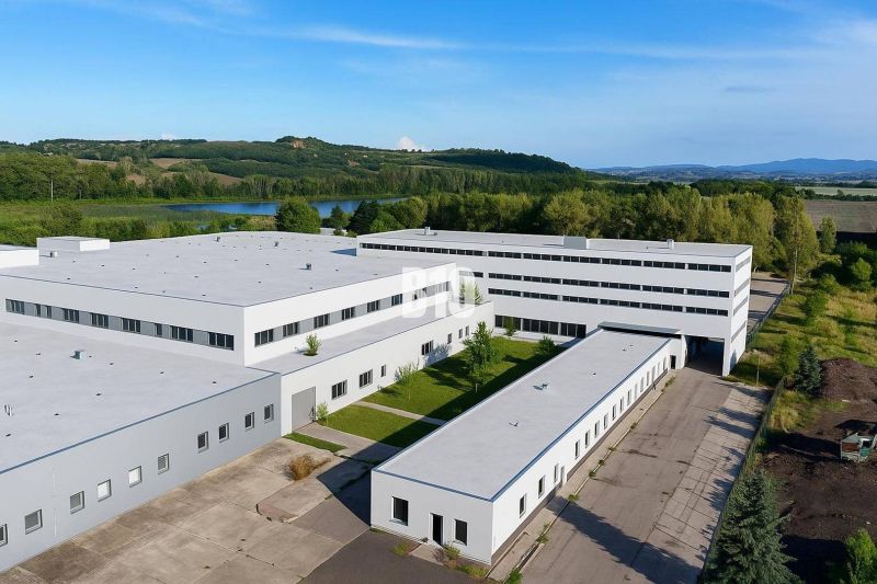 Veľkometrážne VÝROBNÉ HALY v priemyselnej zóne Géňa - Levice - Výrobné priestory v Leviciach s upraveným areálom, obklopené zeleňou a rybníkom.