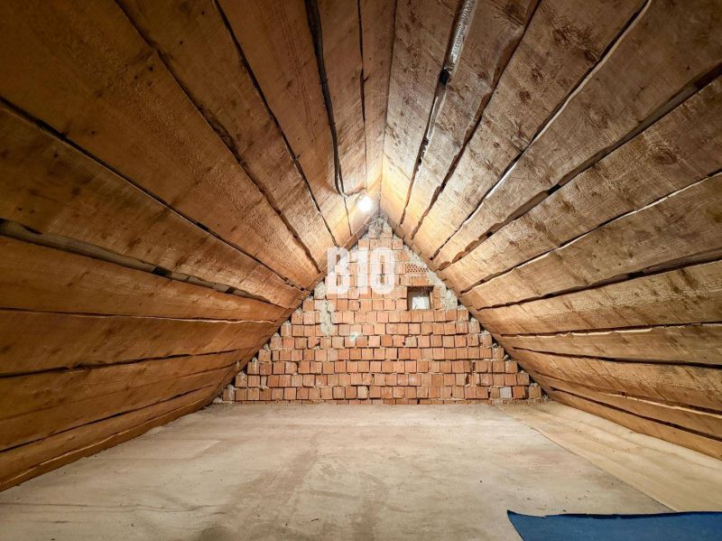 Priestranný rodinný dom s garážou na veľkom pozemku v obci Vlkas - Podkrovný priestor s drevenými stenami a tehlovou stenou v rodinnom dome.
