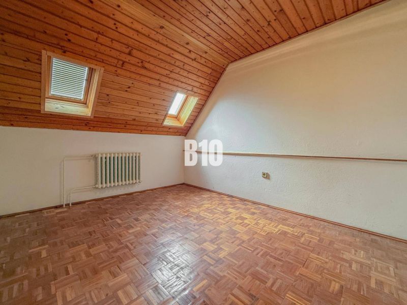 Priestranný rodinný dom s garážou na veľkom pozemku v obci Vlkas - Izba v rodinnom dome s dreveným obkladom a podlahou s dreveným dekorom.