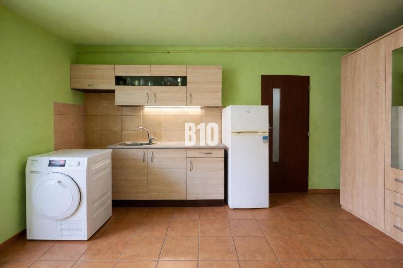 Rodinný dom s dvoma samostatnými bytovými jednotkami – Starý Hrádok - Kuchyňa v rodinnom dome s dreveným dekorom nábytku, zelenými stenami a dlažbou.