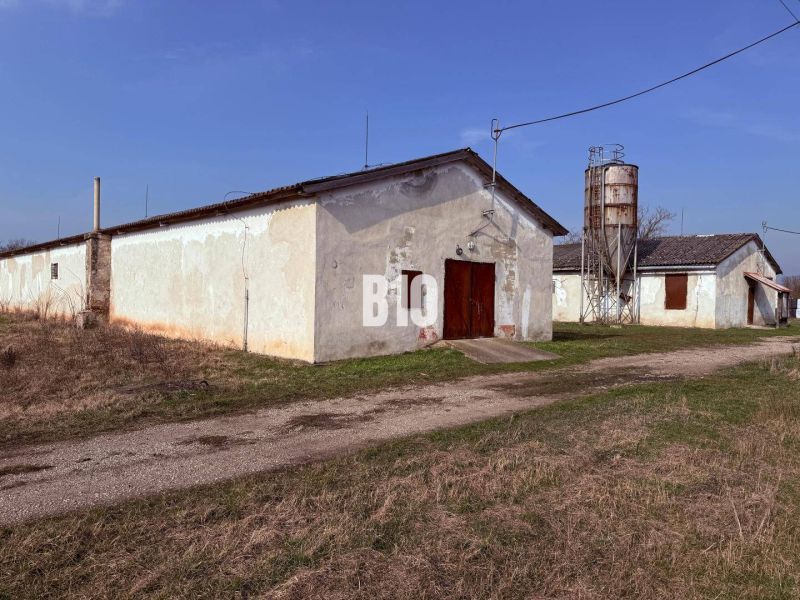 Výhodný hospodársky areál v obci Turá - Výrobné priestory v Turej s poľnohospodárskou architektúrou a silom na pozadí.