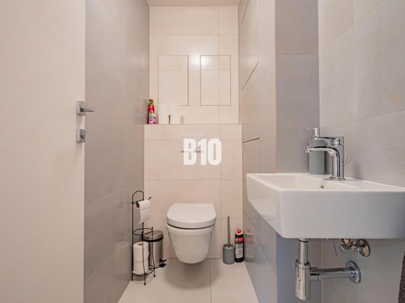 Výnimočný byt s panoramatickým výhľadom na Zobor - Kúpeľňa v 3-izbovom byte s jednoduchými svetlými obkladmi a sanitárnym vybavením.