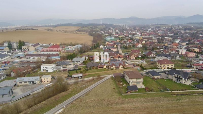 PRESTÍŽNY STAVEBNÝ POZEMOK S PROJEKTOM – ROSINA PRI ŽILINE - Letecký pohľad na obytnú oblasť v Rosine s domami a zeleňou. Pozemky - bývanie.