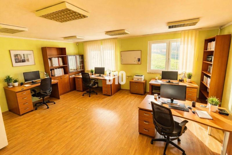 INVESTIČNÁ POLYFUNKČNÁ BUDOVA - Kancelária v budove s podlahou s dreveným dekorom, počítače, stoly, zelené steny, regály.