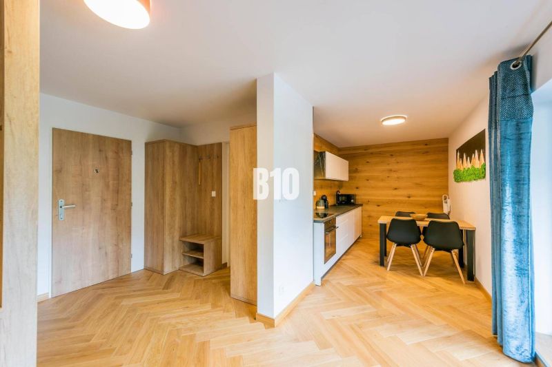 Investičný APARTMÁN v centre Terchovej - Interiér 1-izbového bytu s podlahou s dreveným dekorom a kuchynským kútom.