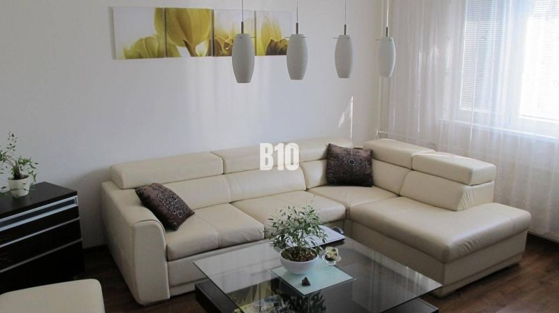 Priestranný 4 izbový byt - Solinky - Elegantná obývacia izba v 4-izbovom byte s krémovou sedačkou a podlahou s dreveným dekorom.