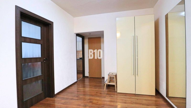 Priestranný 4 izbový byt - Solinky - Interiér 4-izbového bytu s podlahou s dreveným dekorom, skriňou a zrkadlom.