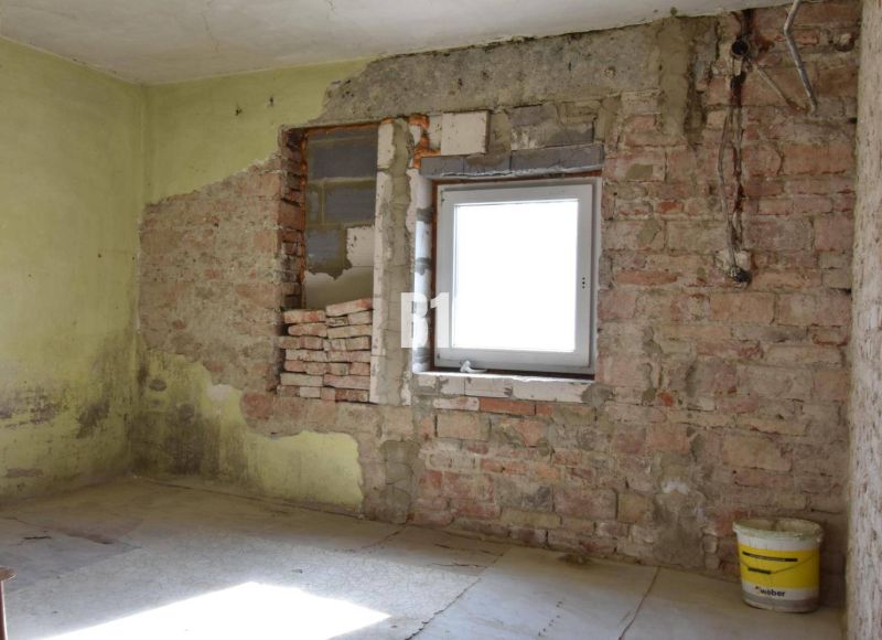Rodinný dom na rekonštrukciu, 660m2 pozemok. - Izba v rodinnom dome s tehlovými stenami a vedrom na podlahe.