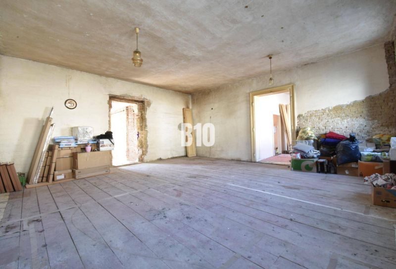 Rodinný dom na rekonštrukciu, 660m2 pozemok. - Neporiadna miestnosť v rodinnom dome s drevenou podlahou a stavebným materiálom.