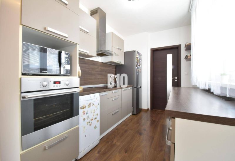 3-izbový byt s parkovaním vo dvore - Kuchyňa v 3-izbovom byte s podlahou s dreveným dekorom a modernými spotrebičmi.