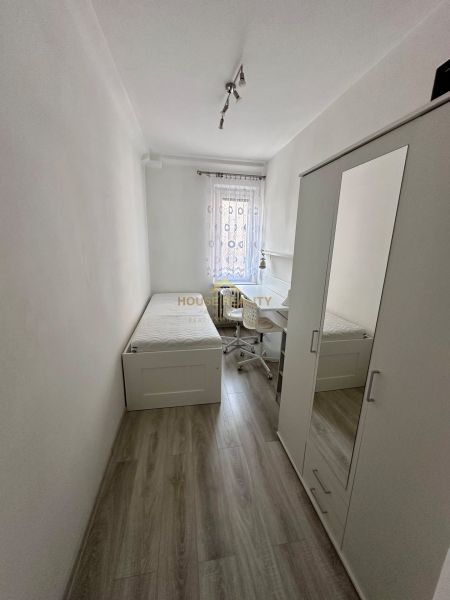 Prenájom moderný 2,5 izbový byt, Šalviová ulica, Bratislava II.Ružinov - Jednoduchá izba s posteľou, skriňou a stolom, podlaha s dreveným dekorom.