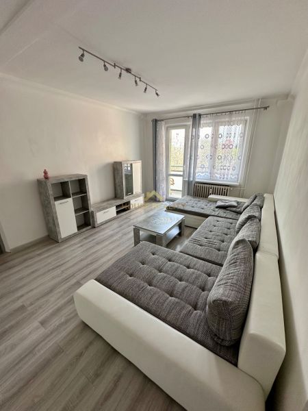 Prenájom moderný 2,5 izbový byt, Šalviová ulica, Bratislava II.Ružinov - Obývačka v 3-izbovom byte s podlahou s dreveným dekorom, veľkou sedačkou a televíziou.