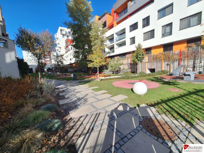 Ponúka na prenájom garsónku v komplexe Čerešne, Polianky Bratis - Malý park s chodníkom a modernými bytovými domami na Polianoch v Bratislave - Dúbravke.