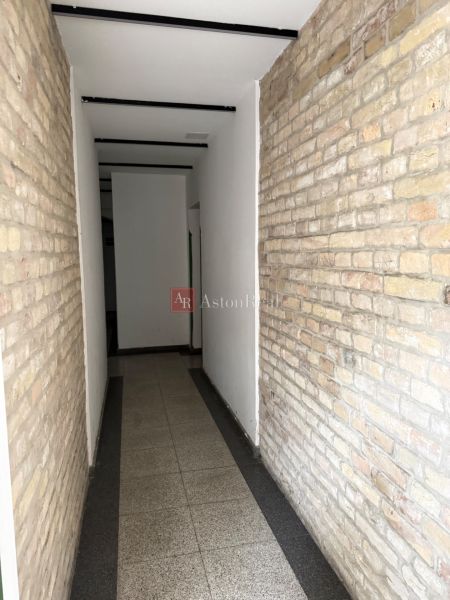VEĽKORYSÝ 2i byt s rozlohou 76 m² v atraktívnej lokalite- Staré mesto - Úzky interiérový priechod s tehlovou stenou a svetlou podlahou v 2-izbovom byte.