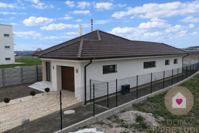 DUNAJSKÁ STREDA- 4i moderná novostavba RD s tep. čerpadlom + garážou - Rodinný dom na Ulici Vojvodcu Arpáda v Dunajskej Strede s tmavou strechou a oplotením.