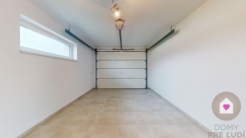 DUNAJSKÁ STREDA- 4i moderná novostavba RD s tep. čerpadlom + garážou - Garáž v rodinnom dome s veľkou vstupnou bránou a oknom na bočnej stene.