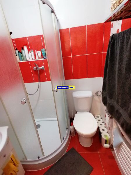 1 izbový byt na predaj rekonštrukcia, Martin centrum, nový balkón - Kúpeľňa v 1-izbovom byte s červenými obkladačkami a sprchovacím kútom.