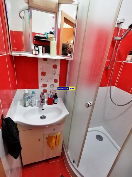 1 izbový byt na predaj rekonštrukcia, Martin centrum, nový balkón - Kúpeľňa s červenými obkladmi, sprchovacím kútom a umývadlom v 1-izbovom byte.