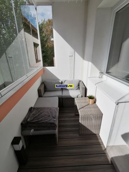 1 izbový byt na predaj rekonštrukcia, Martin centrum, nový balkón - Presklený balkón s ratanovým nábytkom a podlahou s dreveným dekorom v 1-izbovom byte.