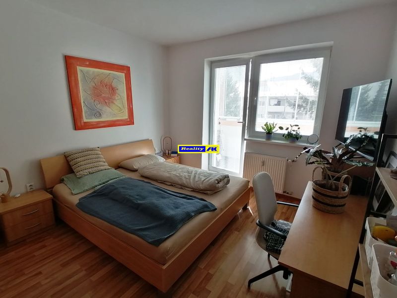 1 izbový byt na predaj rekonštrukcia, Martin centrum, nový balkón - Svetlý 1-izbový byt s podlahou s dreveným dekorom, posteľou a stolom.