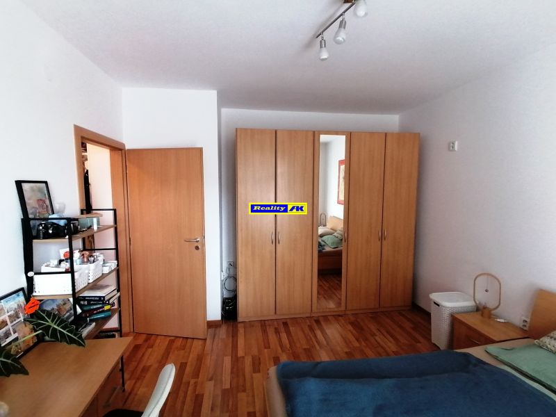 1 izbový byt na predaj rekonštrukcia, Martin centrum, nový balkón - Spálňa v 1-izbovom byte s podlahou s dreveným dekorom, šatníkovou skriňou a písacím stolom.